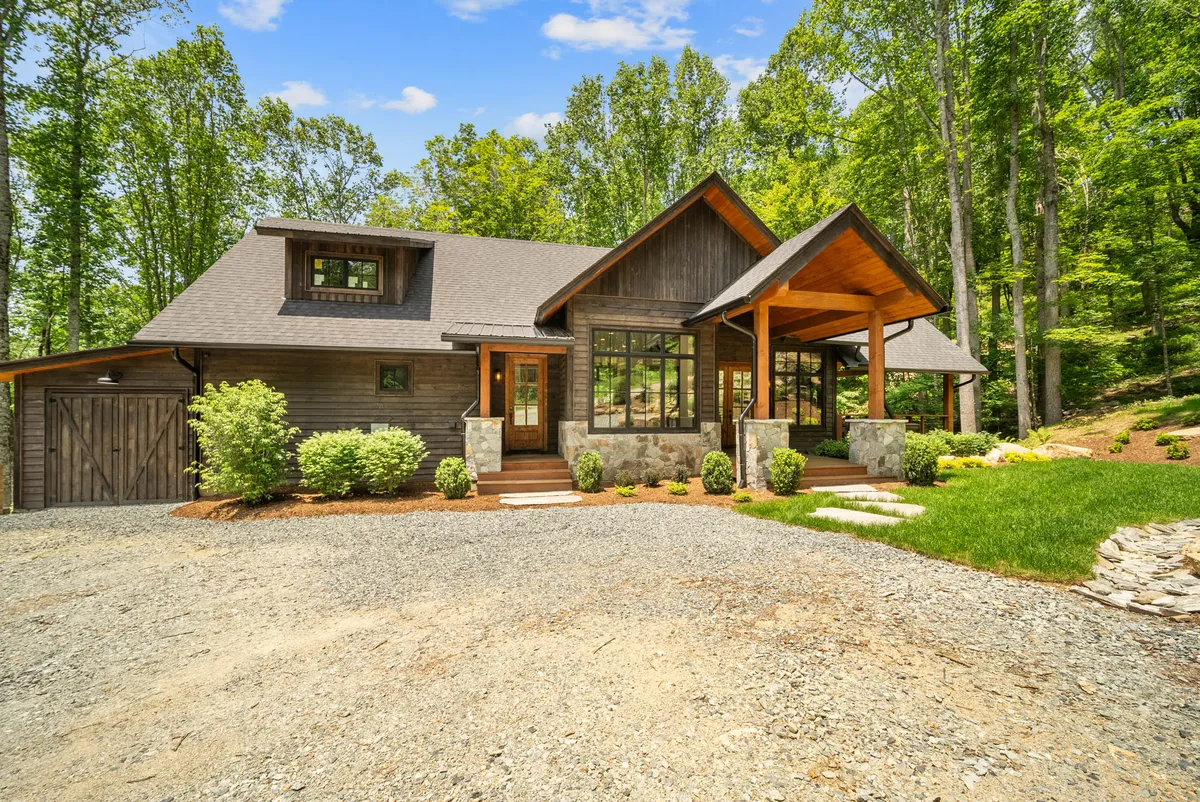 A view of the front porch featuring large windows, stone accents, and a landscaped garden. The porch looks out over natural surroundings, creating a welcoming transition from indoors to the outdoor adventure that awaits.